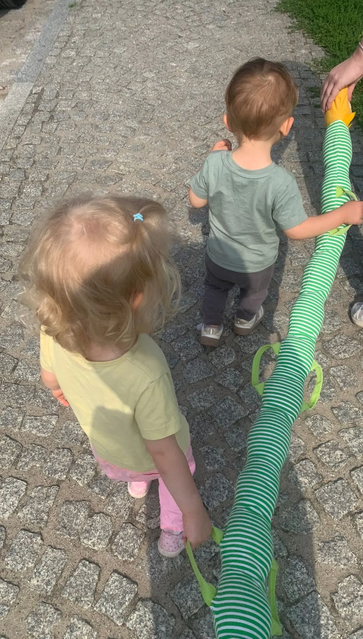 Dwójka dzieci trzymająca się gąsiennicy spacerowej na dworze.